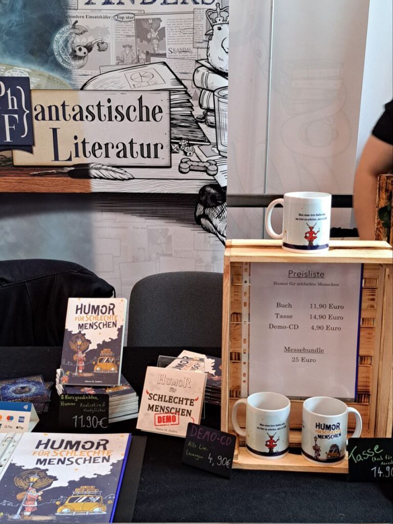 Zu sehen ist das Buch "Humor für schlechte Menschen", sowie die Tasse und die Hörbuchdemo.